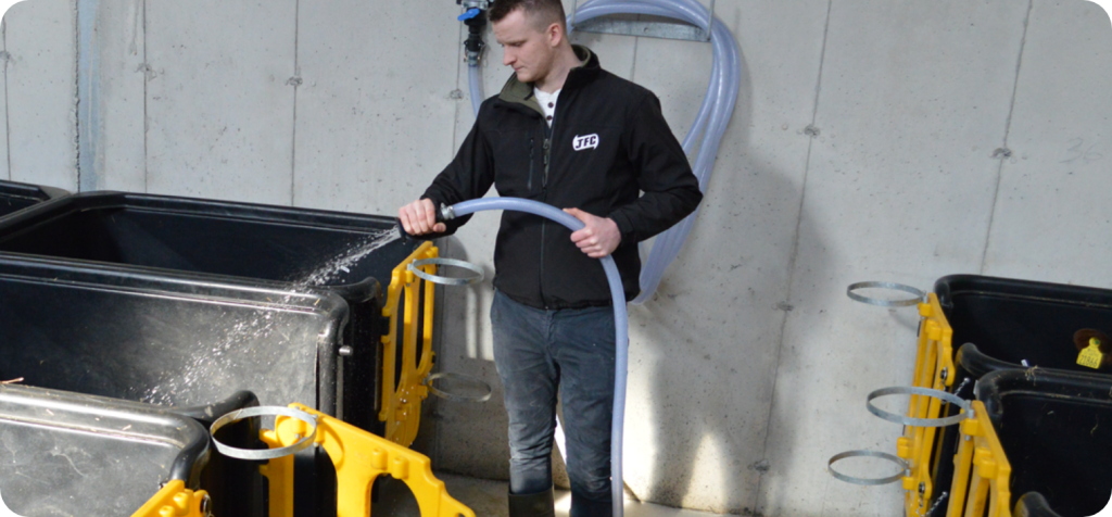 farmer washing our calf isolation units