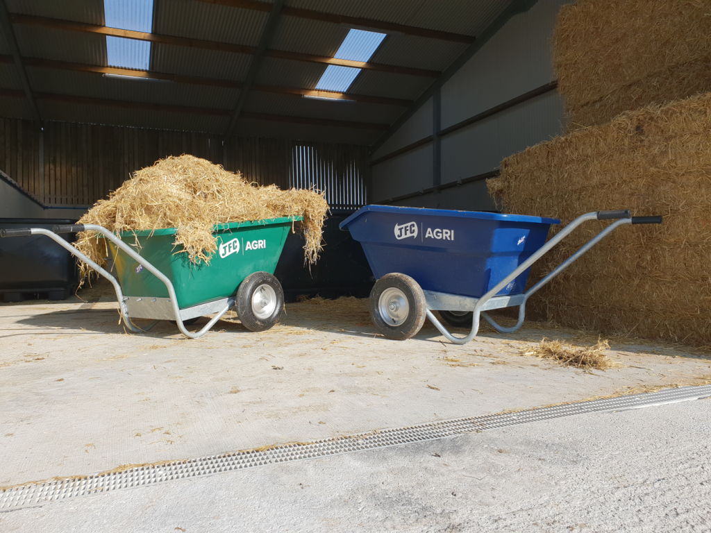 blue and green wheelbarrow with green one full with hay