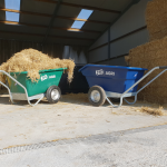 blue and green wheelbarrow with green one full with hay